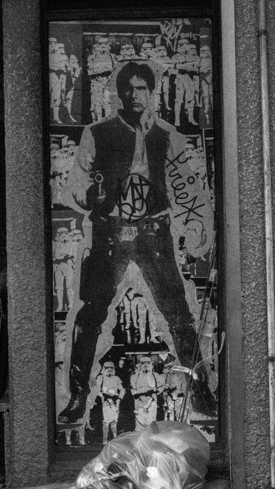 A grafittoed picture of Han Solo facing the camera holding his gun. Tags and spraypaint are scrawled across it.